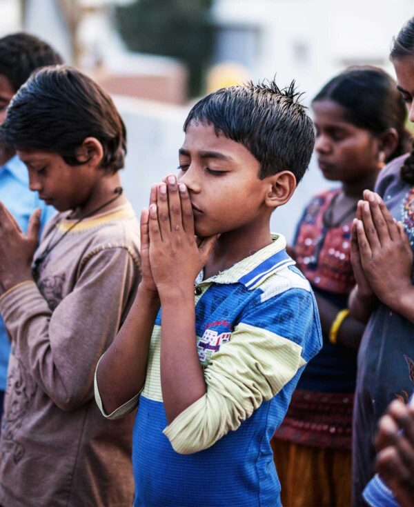 Boy praying in a group.
